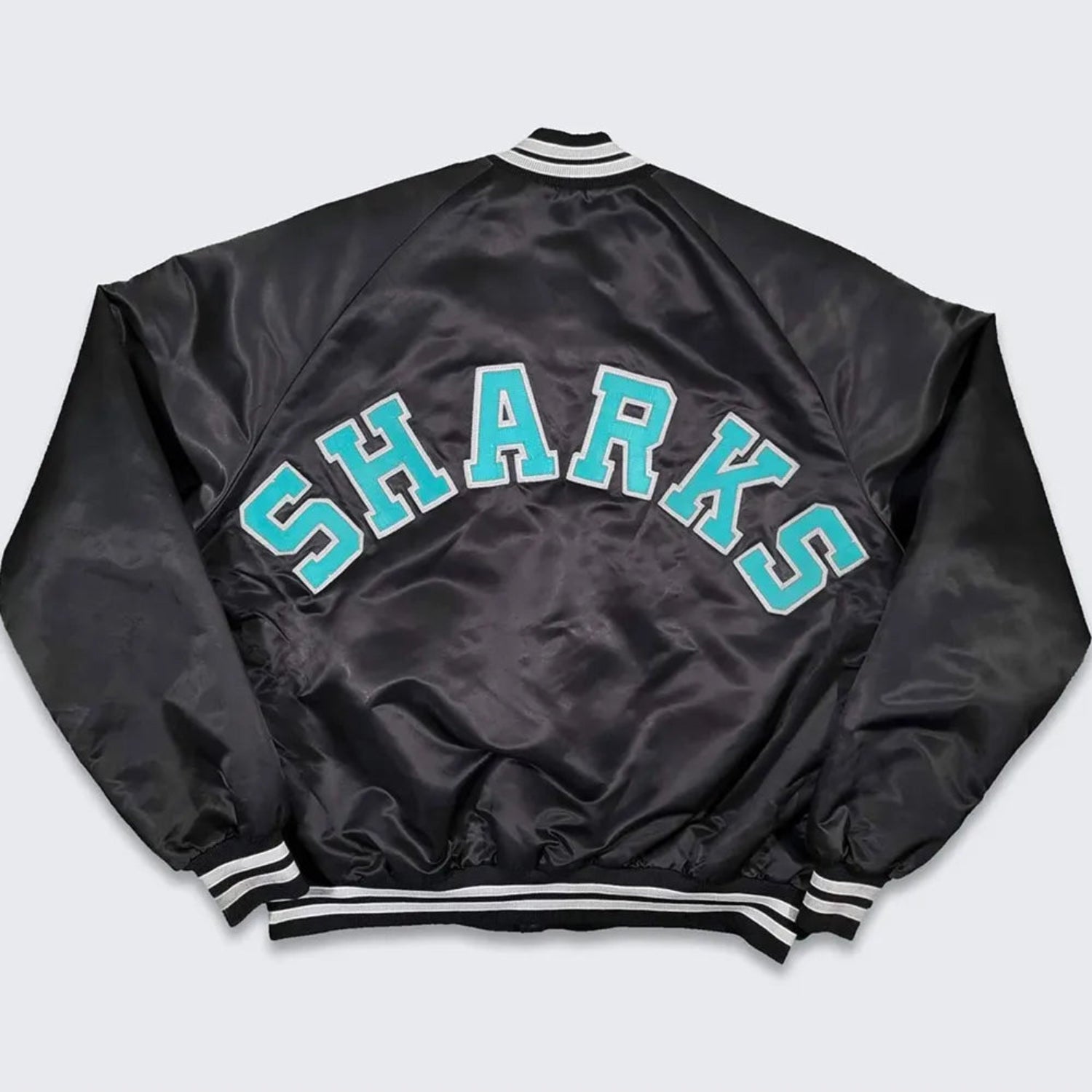 Back of NHL San Jose Sharks satin varsity jacket in black colour featuring large team logo and striped ribbed hem